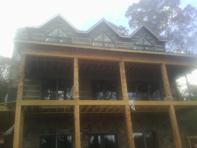 Dormers and porch framing on a large log home under construction — Roof Coating work by our crew in Metamora