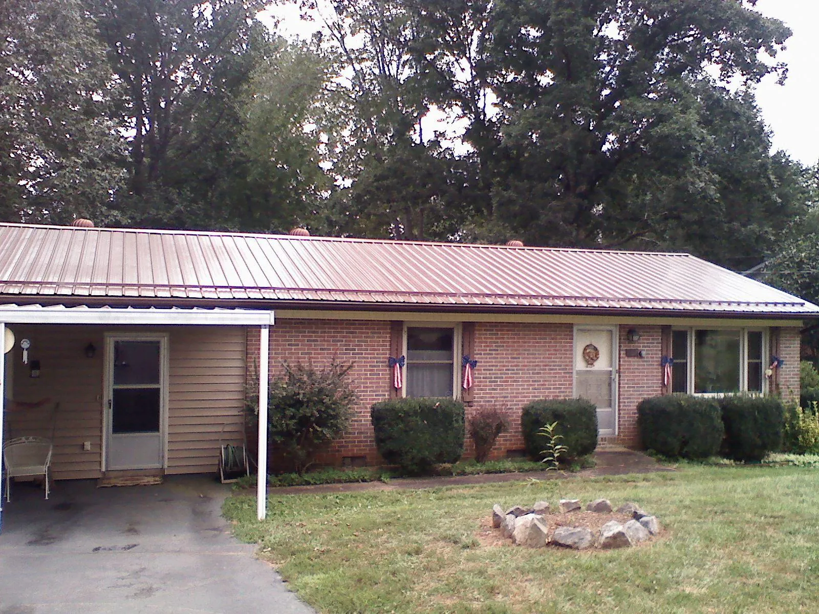 Bronze metal roof and carport on a brick ranch home — Roof Repair work by our crew in Metamora